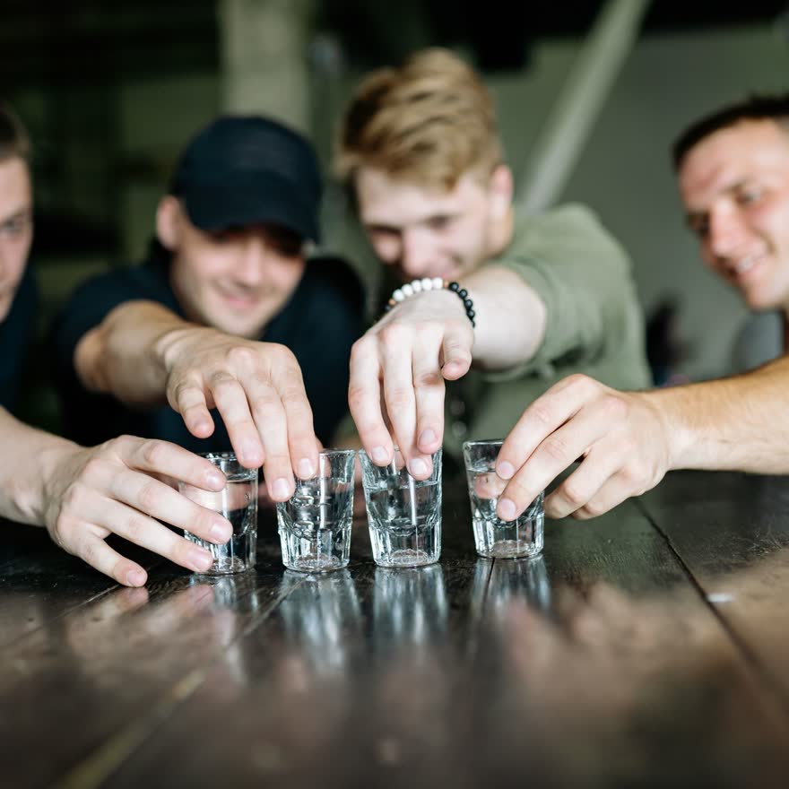 Manos sirviendo shots en una barra antes de la salida